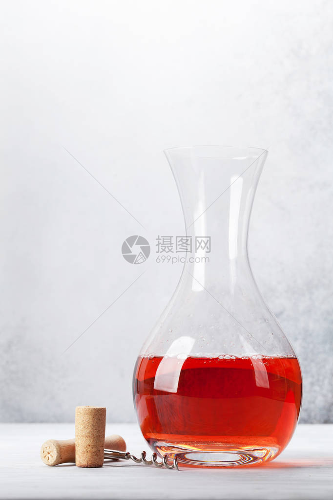 玫瑰酒在木制桌上的玻璃脱落器中在石墙前图片