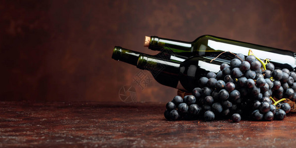 棕色背景的果汁蓝葡萄和红酒瓶子图片