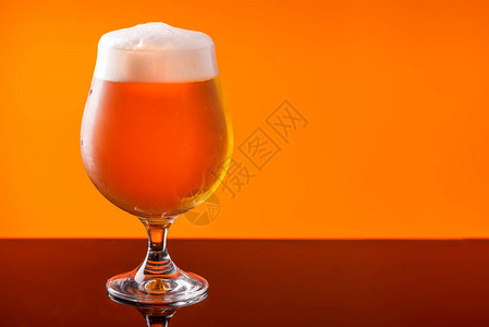 啤酒杯和橙色背景的酒滴酒精概图片