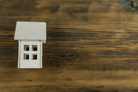 具有木材背景的旧钥匙的微型房屋不动产概念图片