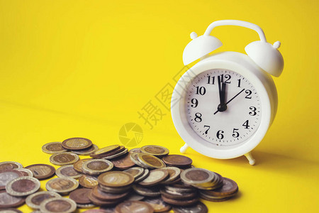 黄色背景上的闹钟和钱币财务概念商业背景退休财务和为图片