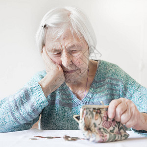 岁的老妇人可怜巴地坐在家里的桌子旁图片
