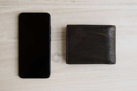黑手机和木制桌上的棕色皮钱包图片