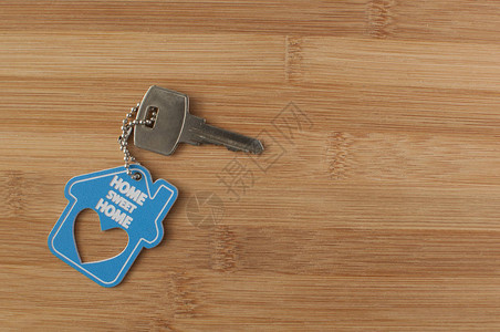 在木制背景的房屋形状钥匙链上贴紧房钥匙不动产搬家或租赁财产的图片