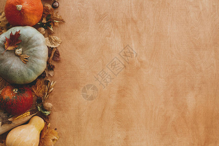 南瓜秋叶玉米核桃栗子橡子在质朴的木桌上图片