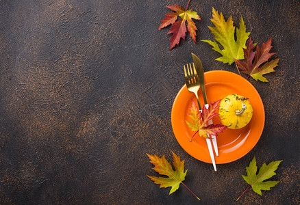 秋天的餐桌设置与五颜六色的枫叶背景图片
