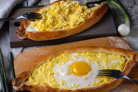 有两个人吃Adzharkhachapuri奶酪鸡蛋和黄油图片