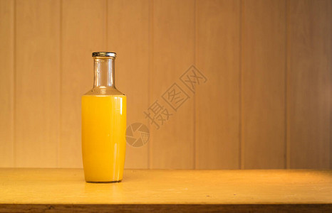 装有苹果汁的大玻璃瓶在木制背景图片