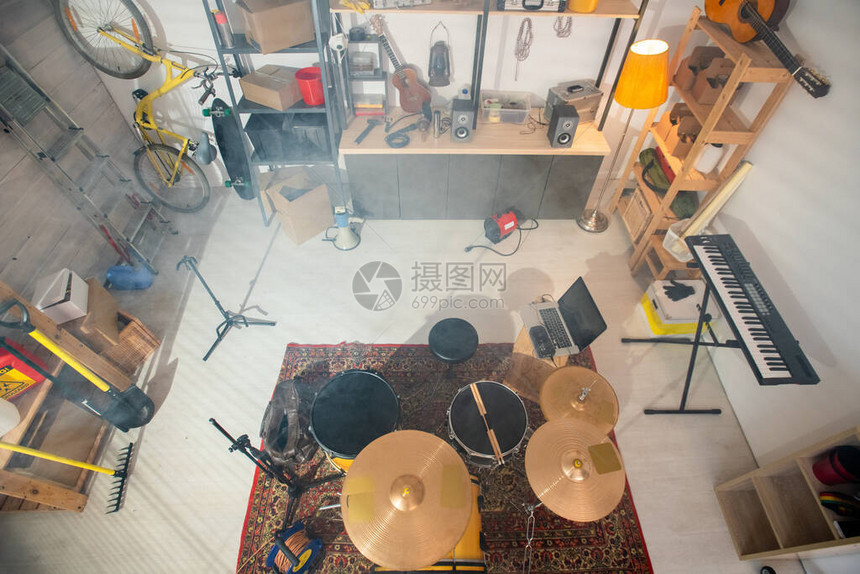 地毯上的鼓组钢琴板吉他和其他乐器笔记本电脑工作具木架子和车库图片