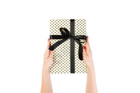 女人的手用黄纸用黑丝带包裹圣诞或其他节日手工礼物图片