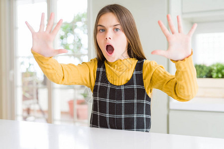 在家穿着休闲黄色毛衣的金发美女小孩用手掌愤怒和沮丧的表图片