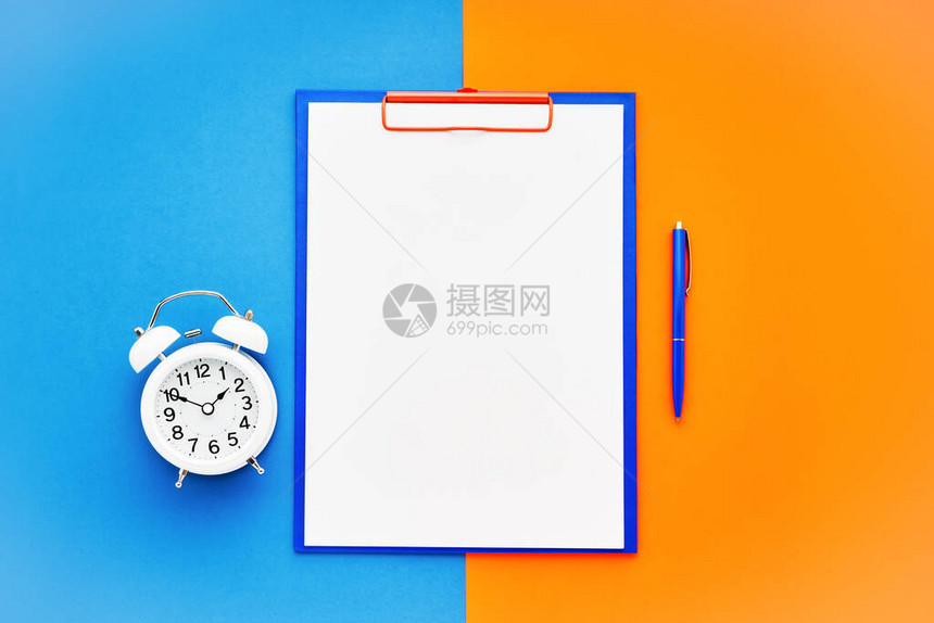 空白剪贴板模型蓝色笔和蓝橙色背景上的白色闹钟图片