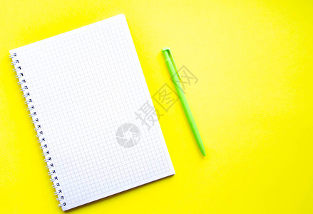 黄色背景上的平方笔记本绿色和黑色的笔和记本笔记本图片