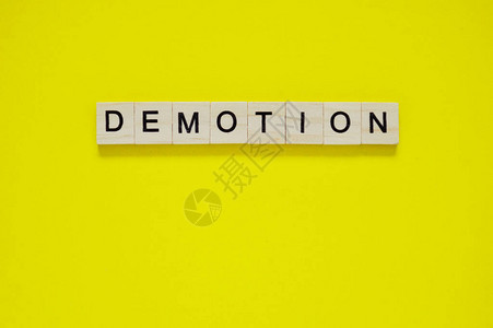 词降级在黄色背景上带有刻字的木块黄色表面带有字母的木图片