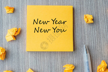 新年你在黄色便条上用钢笔和碎纸在木桌背景上的字决议战图片