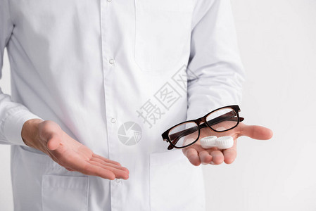 眼科医生用手指着眼镜和片容器在手掌上的剪影图片