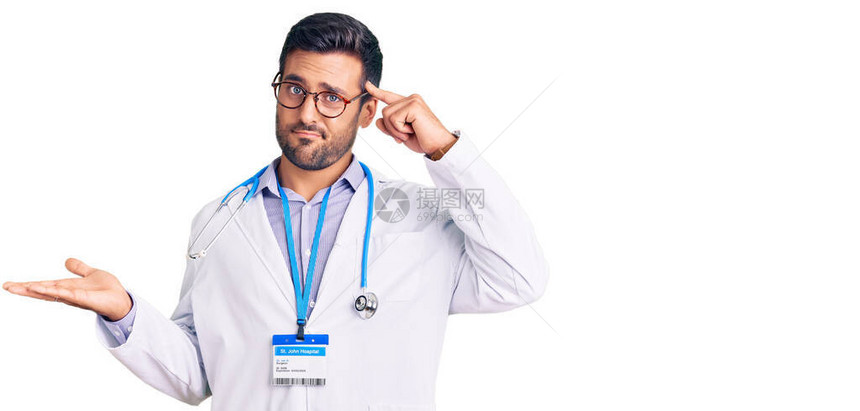身着医生制服和听诊器的年轻西班牙男子困惑与烦恼图片