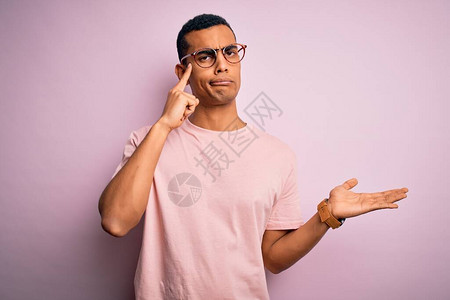 英俊的非洲裔美国人穿着休闲T恤和粉红色背景的眼镜图片