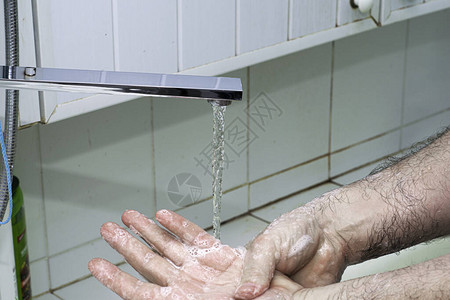 一个男人用肥皂和水洗手在浴室的图片