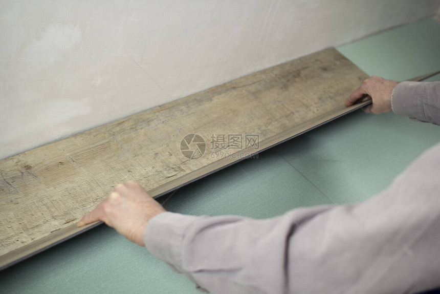 乙烯基层压板铺设地板一名工人在地板上安装一块新图片