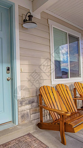 全景棕色木椅在房子阳光照射的门廊的窗户前浅蓝色前门旁边的墙上安装图片