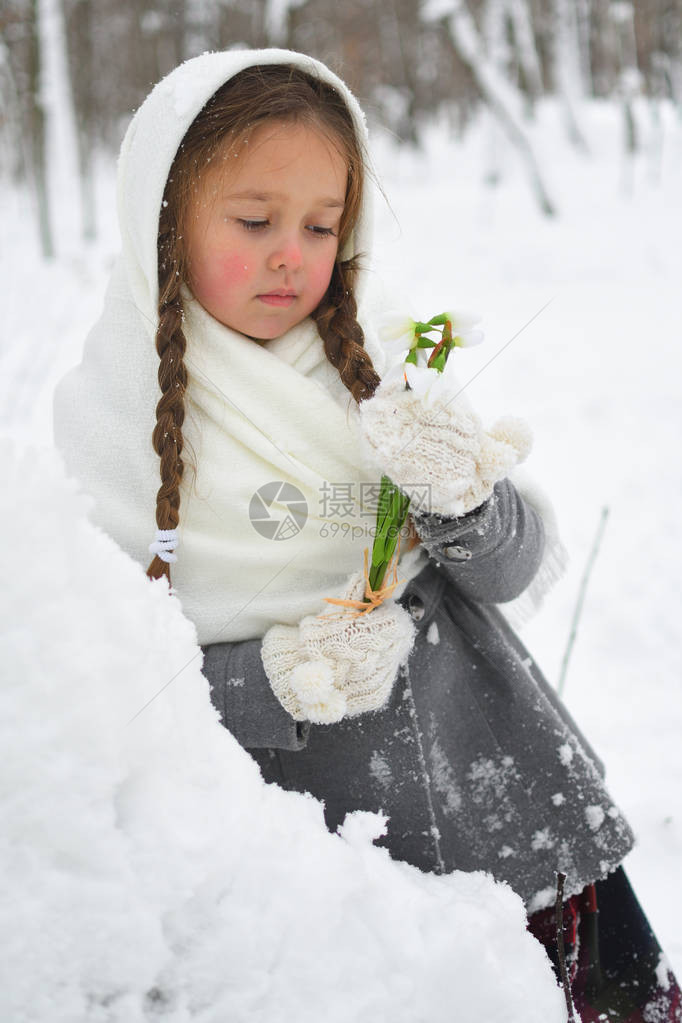 身穿披肩和手套的小女孩在雪地上采雪图片