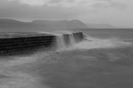 海浪在Dorset的LymeRegis码头撞上时长的暴背景图片