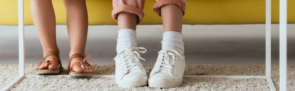 穿运动鞋的保姆和穿着凉鞋的儿童在地板毯附近的拖图片