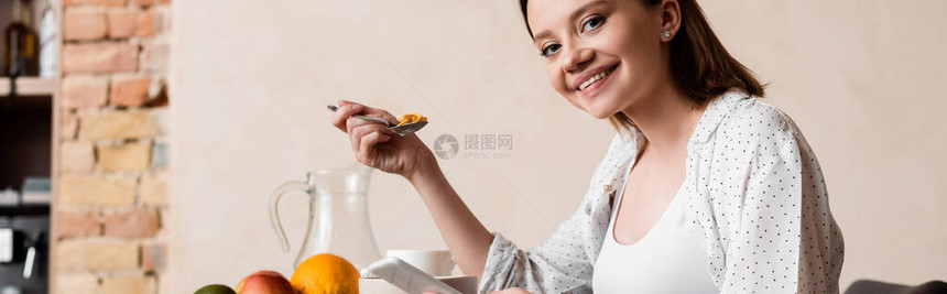 孕妇用玉米片和智能手机拿勺子的图片