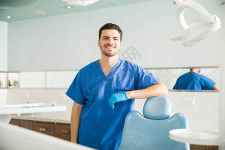 微笑的成人中年牙医在牙科诊所坐着椅图片