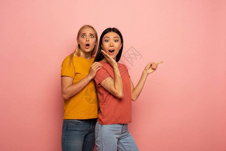 两个女孩表明了什么惊讶和惊讶的表情粉红色背景图片