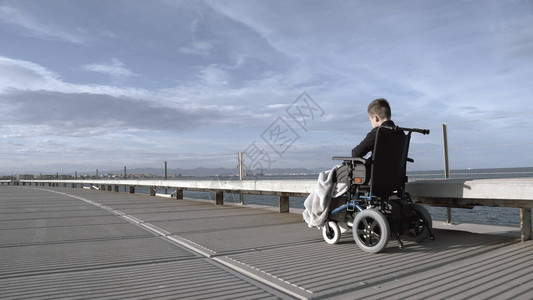 残疾儿童在这个大活跃的世界里无助在户外单独坐在轮椅上的残疾男孩图片