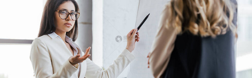 身戴眼镜的女商人在翻页图旁拿着笔记号图片