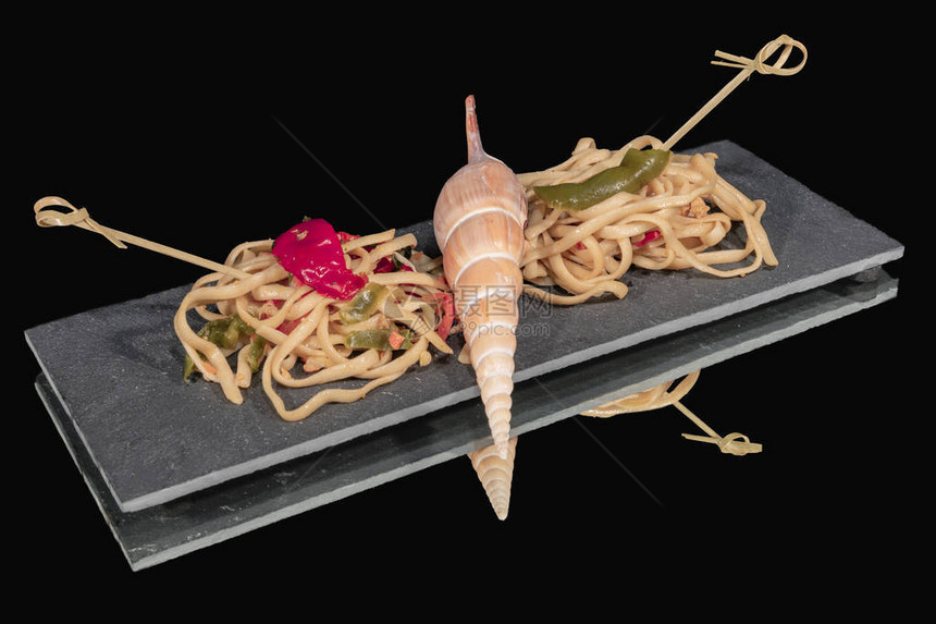意大利面条在贝壳旁边的黑石板上卖意大利面粉图片