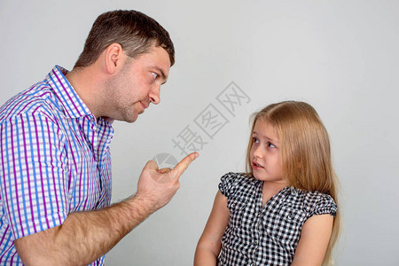 工作室拍到一个愤怒的父亲在灰色背景下责骂或惩罚一个小女儿图片