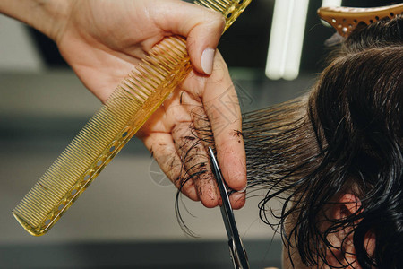 美发师的特写镜头在沙龙里剪掉客户湿漉的棕色头发理发师剪女人用剪刀头图片