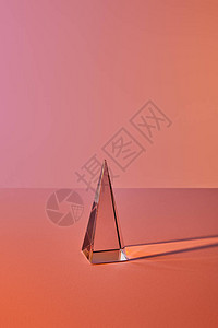 橙色背景上具有光反射的水晶透明金字塔背景图片