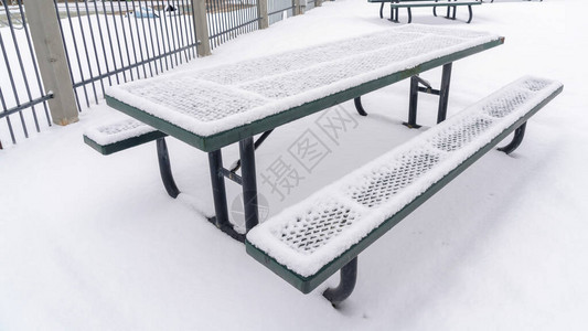全景公园野餐桌和长椅与雪覆盖在地上图片