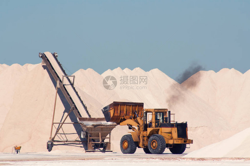 露天的盐厂挖掘机收集盐图片