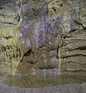带水池的地下石灰岩洞穴中地质岩层的特写细节图片