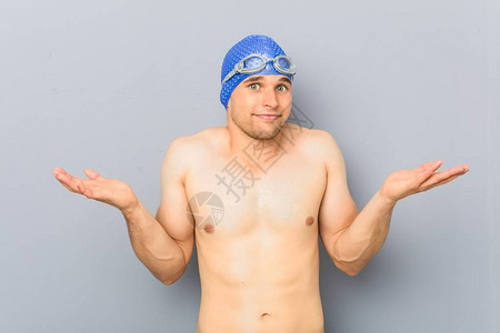 年轻的职业游泳运动员在问话动作中怀疑和挥舞图片