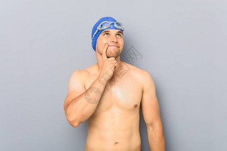 年轻的职业游泳运动员看着侧面充满怀疑和怀疑的表图片