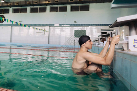 穿着黑色泳裤和泳帽的男游泳教练正在出水背景图片