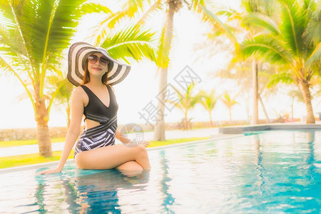 肖像美丽的亚洲年轻女在酒店度假村的室外游泳池周围放松图片