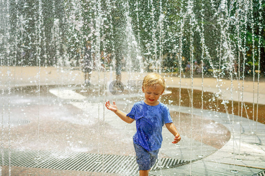 一个男孩在公园喷泉里玩水炎热的夏季快乐的小男孩在喷泉图片
