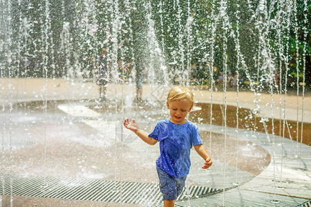 一个男孩在公园喷泉里玩水炎热的夏季快乐的小男孩在喷泉图片
