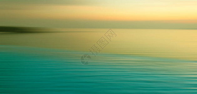 水中折射的模糊背景无穷游泳池与黄昏时海面日落的全景图片
