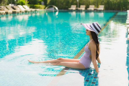 肖像美丽的亚洲女快乐的微笑在酒店度假村的游泳池周围放图片