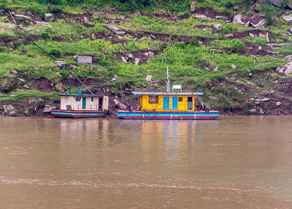 长江2艘五颜六色的船屋停泊在绿色植被和棕色泥土海岸线上图片