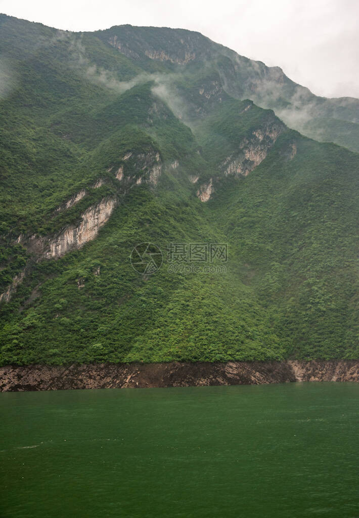 长江上的瞿塘峡灰色的云景沿着绿水后面的绿色覆盖的山坡下降一些米图片